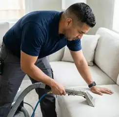 Professional upholstery cleaning technician using an extraction wand to deep-clean a fabric sofa, Overland Park, KS.